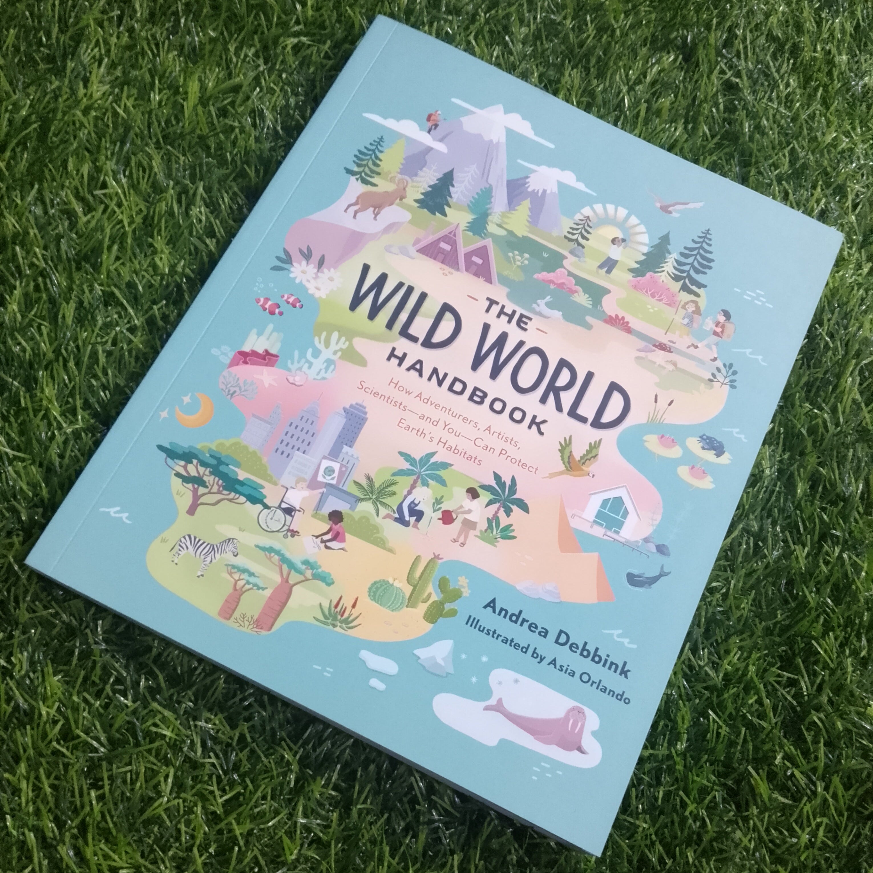 Book titled 'The Wild World Handbook' on grass