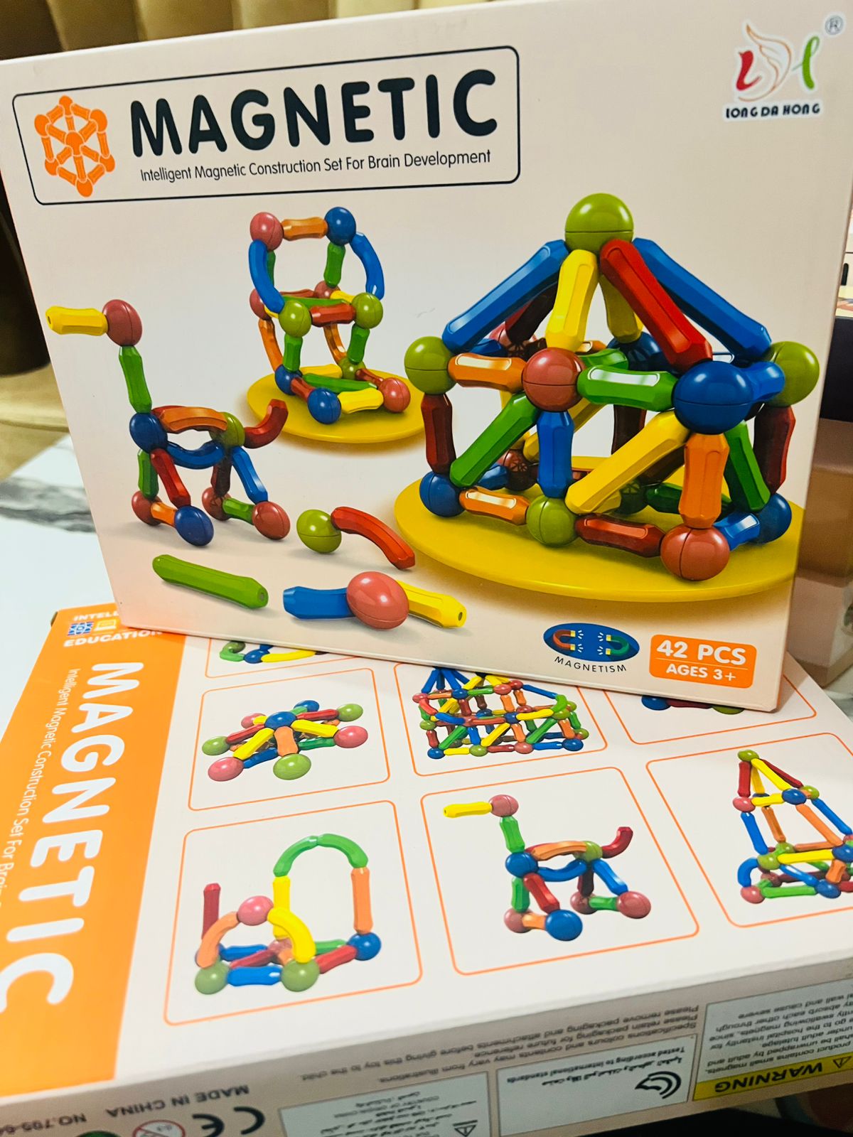Magnetic construction toy set in its retail packaging, featuring colorful plastic building rods and balls on a white box with product images and age information.