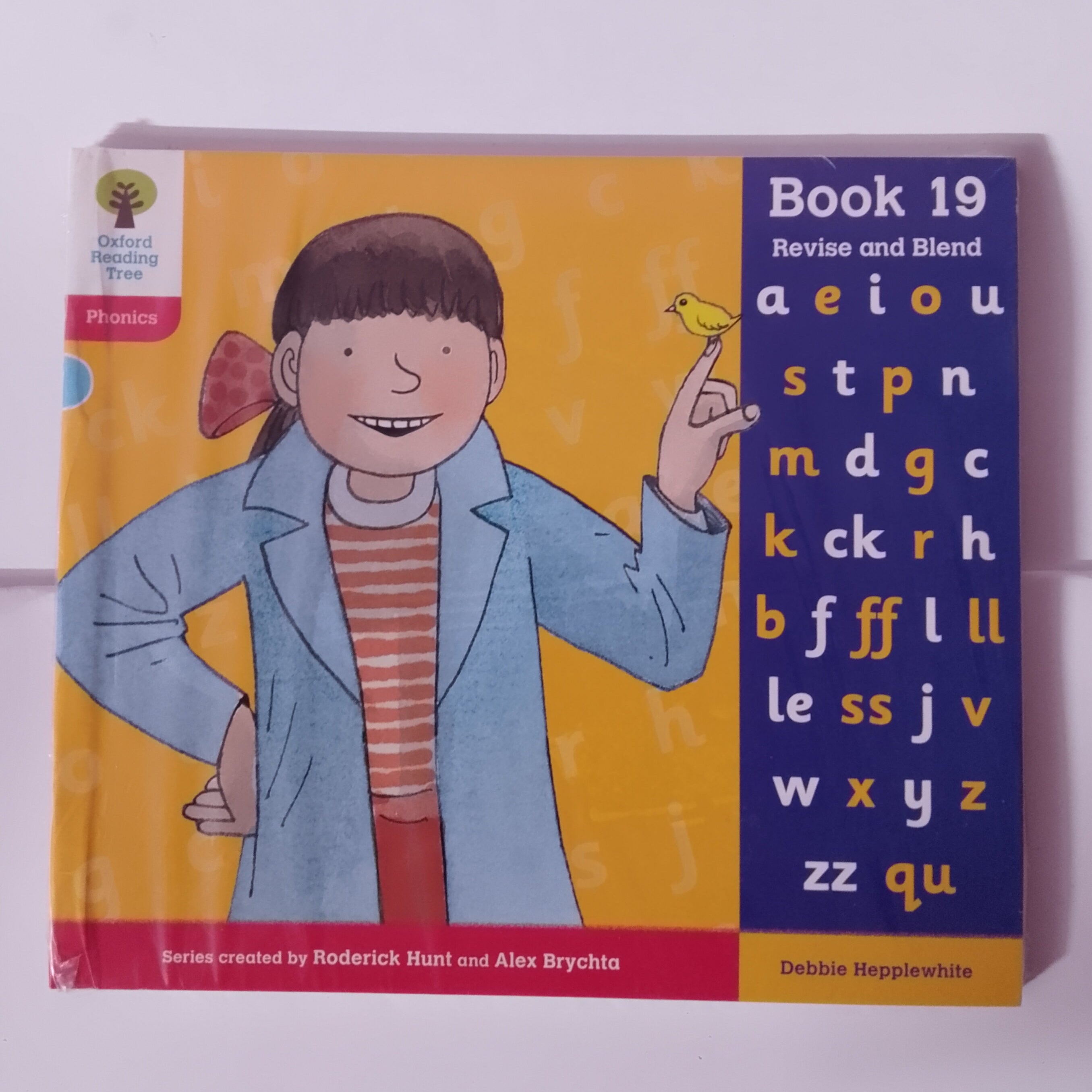 Book cover with a child holding a bird and alphabet letters on a white background