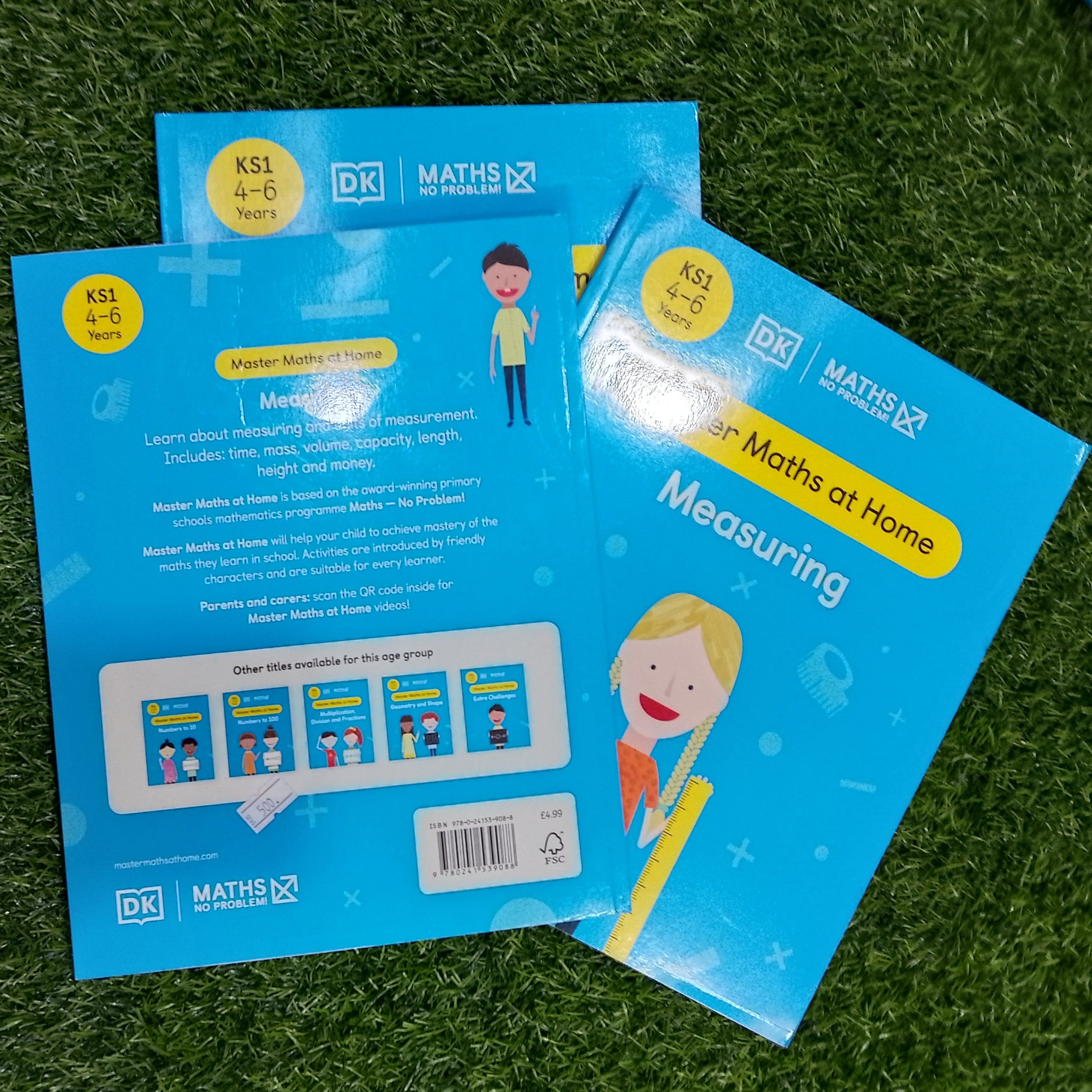Two blue educational books on a green grass-like surface